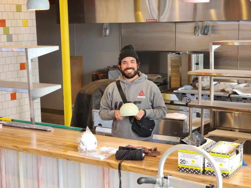 man in hat and gray sweatshirt standing behind counter