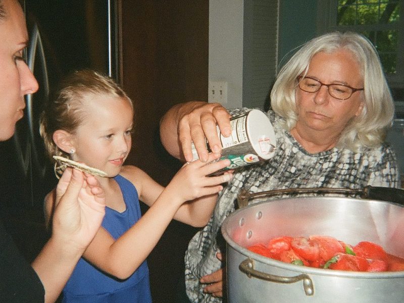 An older woman pours salt in a large pot while a child helps