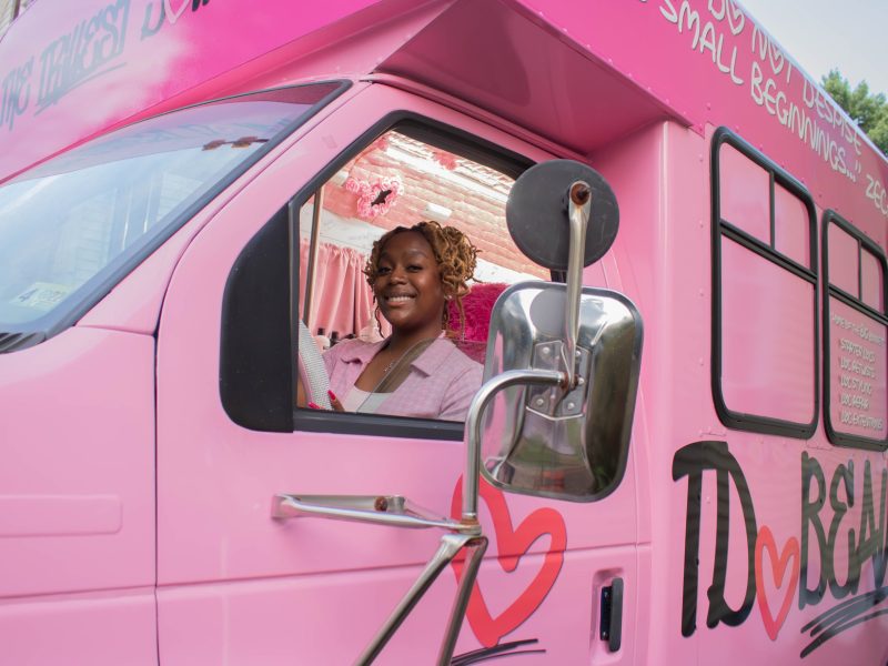 Lauren Kelly smiles in her mobile hair salon, "The TrillestDollhouse Mobile Loc Shop," in June 2024. Photo by Maggie Jones.