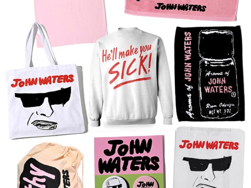 Shirts, bags, and other items display quotes from some of John Waters's movies and illustrations of the filmmaker himself in sunglasses.