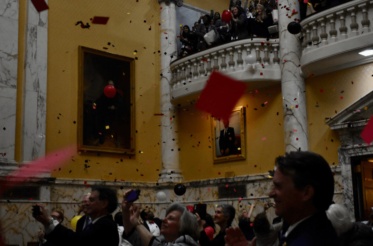 Lawmakers in the Senate chamber celebrate as confetti and balloons scatter down from the balcony at midnight, marking the end of the legislative session. Photo credit: Kiersten Hacker/Capital News Service.