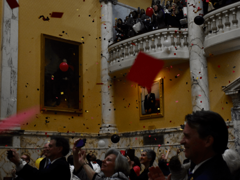 Lawmakers in the Senate chamber celebrate as confetti and balloons scatter down from the balcony at midnight, marking the end of the legislative session. Photo credit: Kiersten Hacker/Capital News Service.