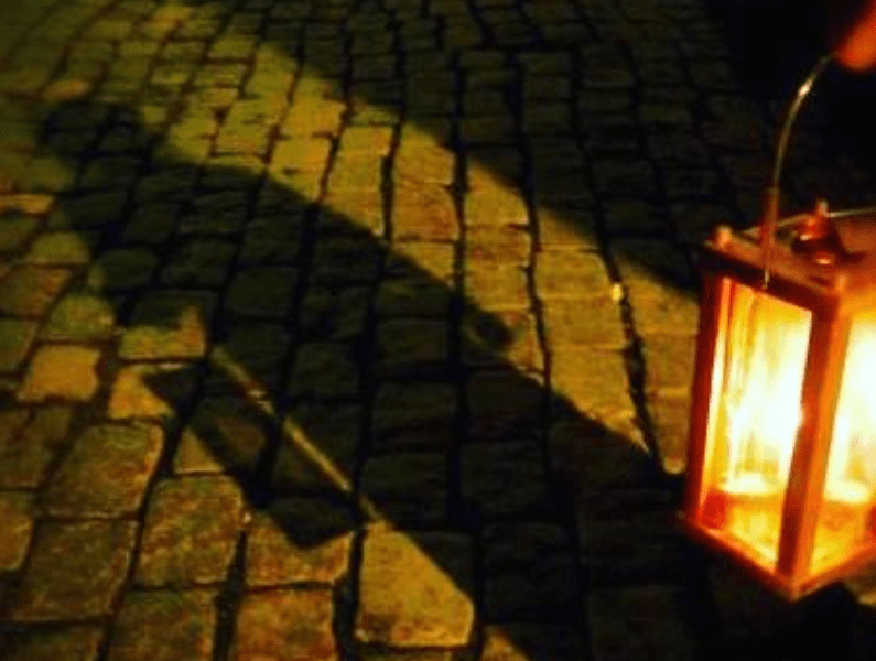 lantern casting a shadow on a cobblestone walkway