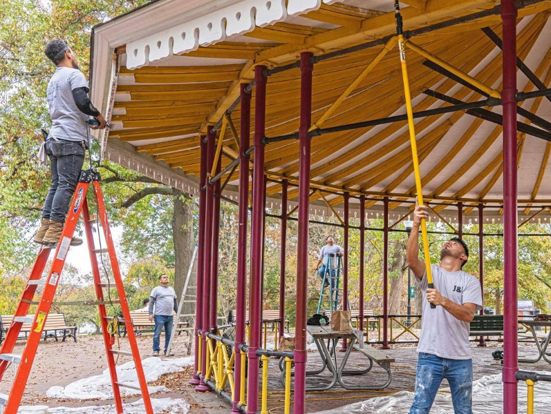 two people working on repairing the roof of a gazebo