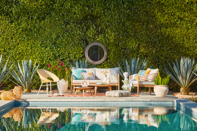 Outdoor pool/patio furniture, floral tans and greens with shrubs behind and pool in front