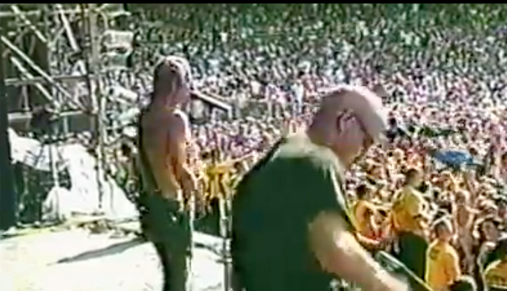 2 rock musicians on stage playing for crowd of thousands