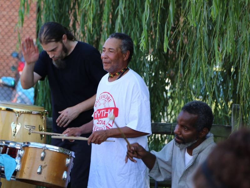 three men playing drums outdoors