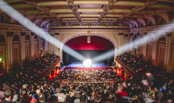 photo of lyric theater, baltimore, inside, from balcony, two spotlights on center of stage, all seats filled