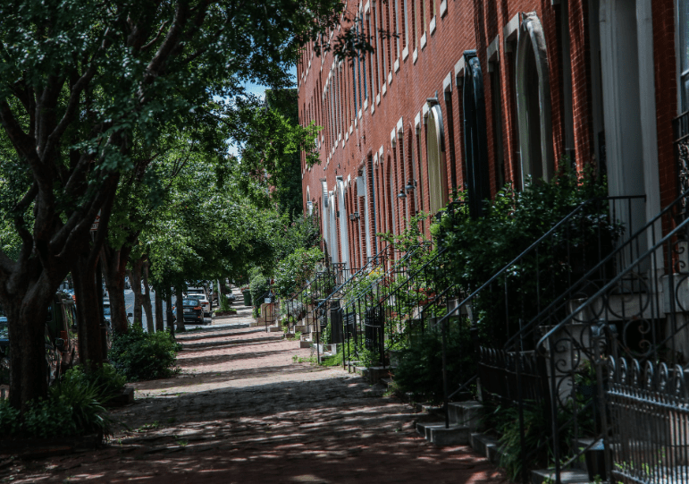 tree-shaded block of brick rowhouses