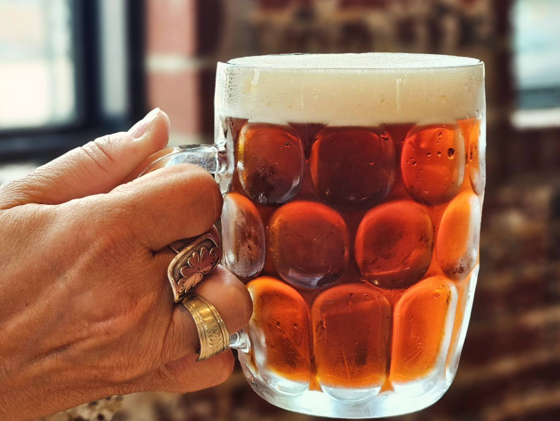 hand holding full beer mug of beer