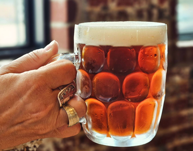 hand holding full beer mug of beer