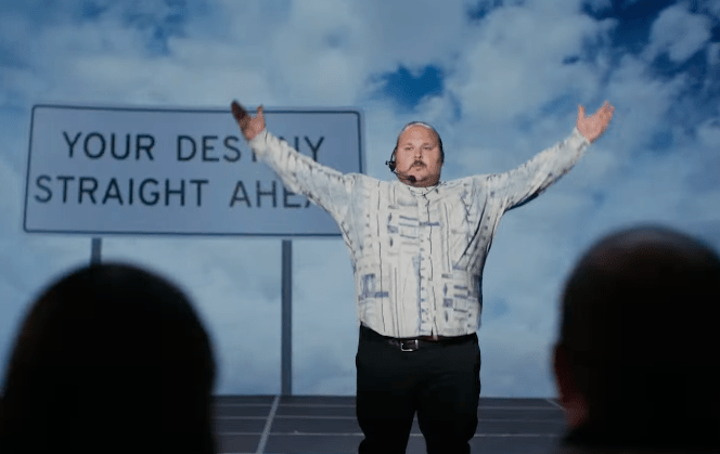 man in button down shirt with arms raised to sides with blue sky behind him and sign that reads "your destiny straight ahead"