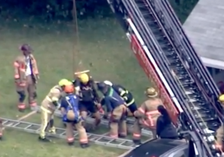 skyshot of fire crews lifting man out of well