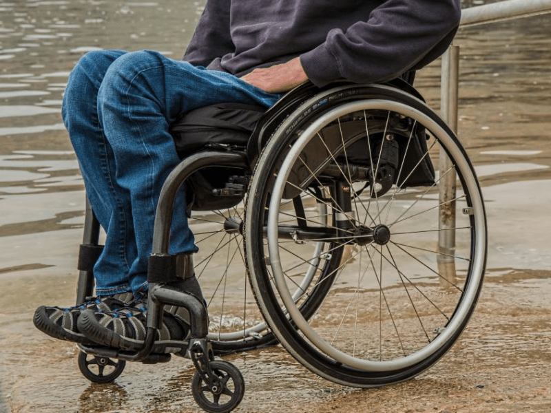 chest down shot of man in wheelchair on sand by ocean