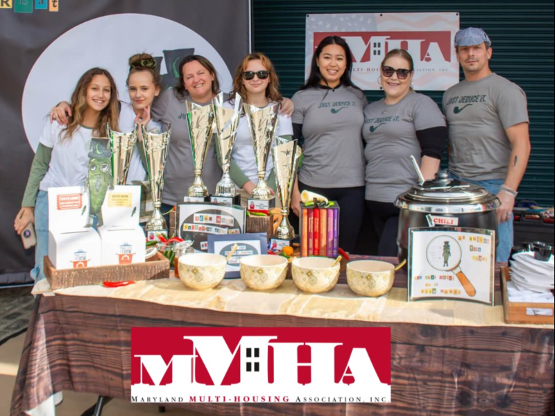 7 people standing behind table with trophys and crockpot smiling