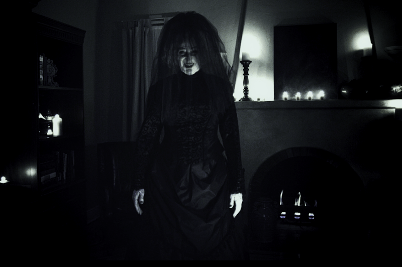 b&W photo of dark room and woman dressed in black with only hands and face partially lit