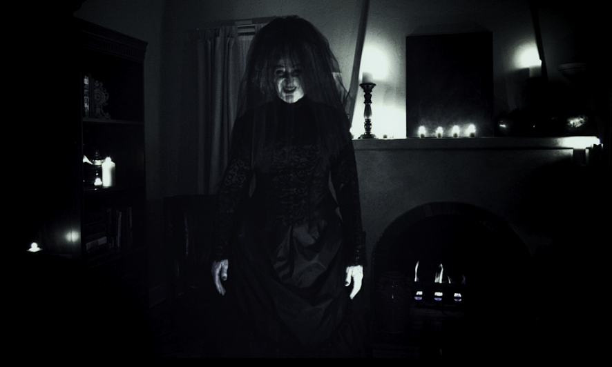 b&W photo of dark room and woman dressed in black with only hands and face partially lit