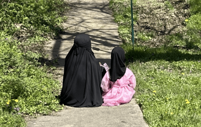 Two Muslim girls sit outside of the Islamic Society of Baltimore following Eid prayers on April 10, 2024. Photo by Wambui Kamau/WYPR.